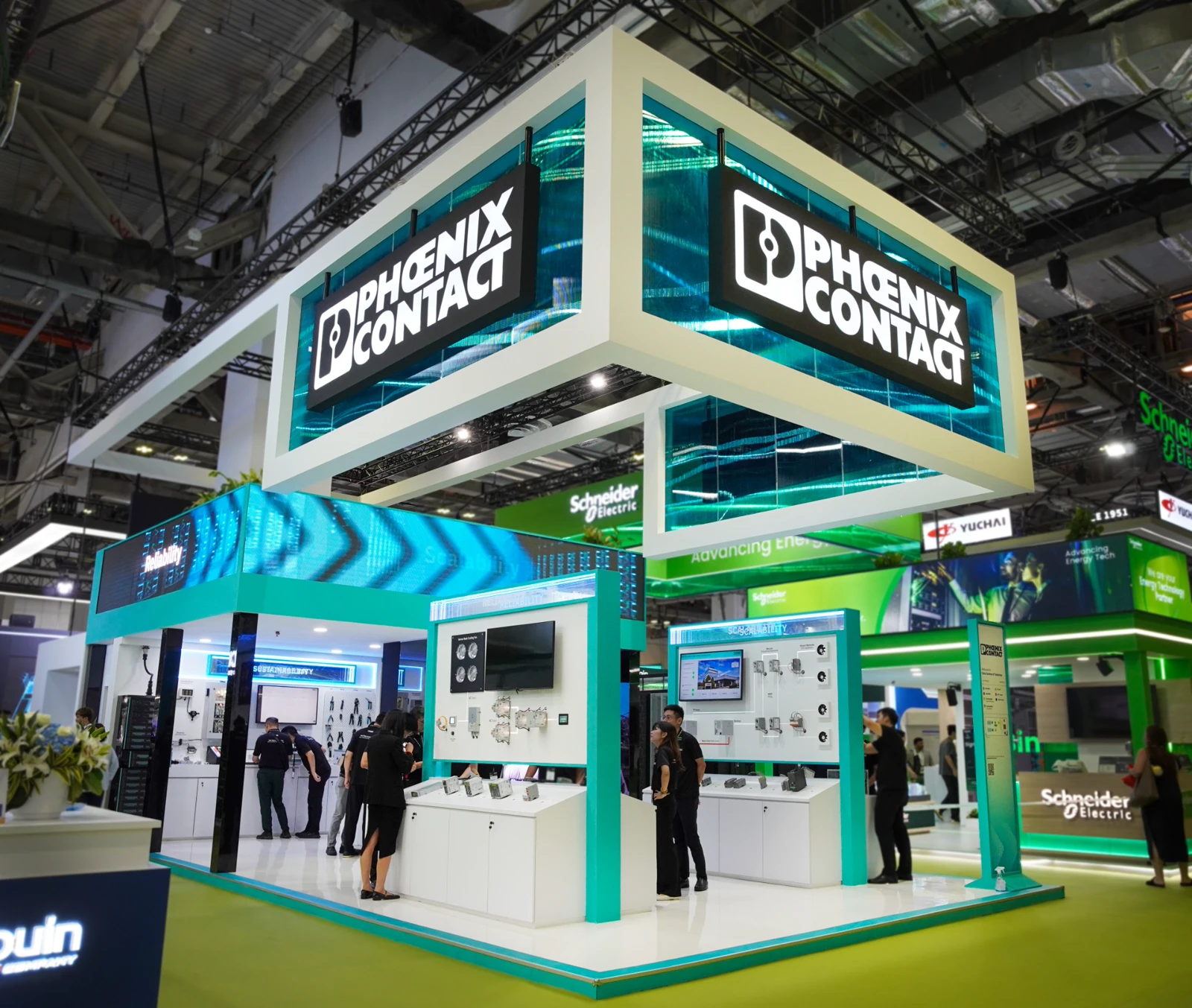 Completed Phoenix Contact exhibition booth with turquoise displays and suspended branding