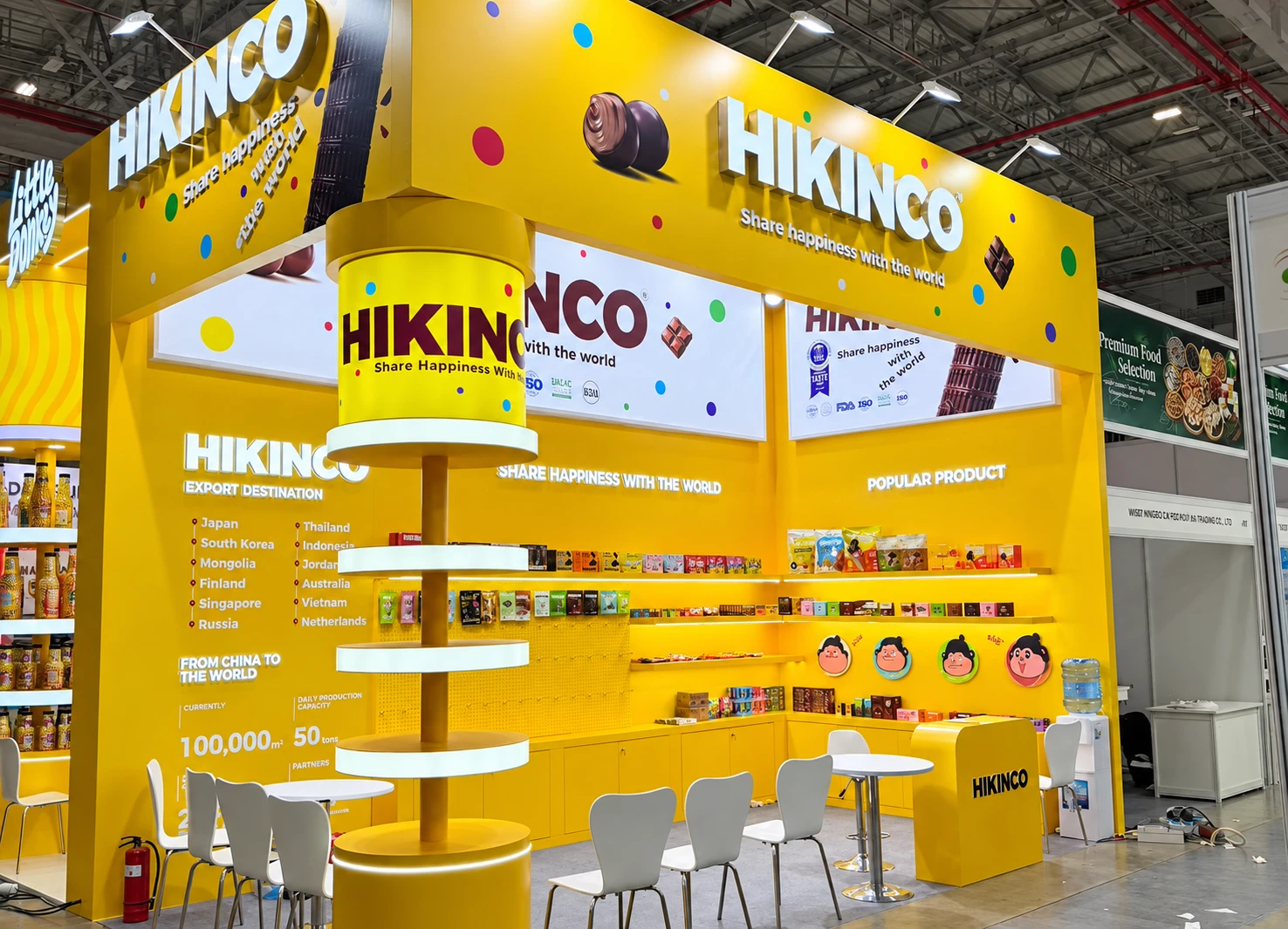 Yellow HIKINCO exhibition booth with suspended branding, product shelves, display counters and white chairs